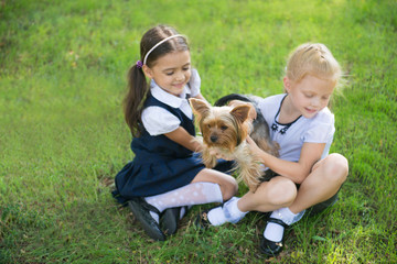 Obraz premium Two girls playing with a dog on the green lawn