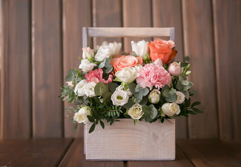 Delicate bouquet of roses, eustomams and carnations with eucalyptus branches on a dark wooden background