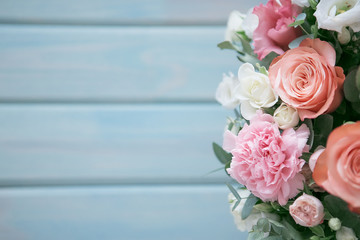 Delicate bouquet of roses, eustomams and carnations with eucalyptus branches on a light blue wooden background