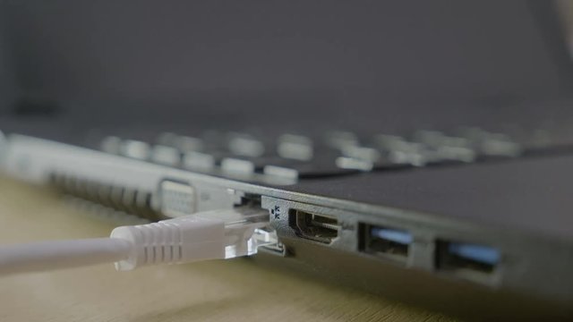 Close up of a male hands connecting and disconnecting the internet white cable from his laptop to repair the network connections