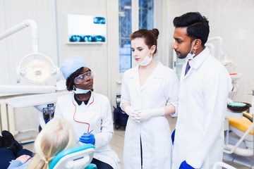 A group of dermatologists of mixed race observe as a professor the girl a black woman heals teeth