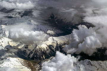 View from the plane to the snowy Alp alps under the clouds