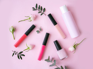 Lip gloss, nail polish with flowers on a pink background