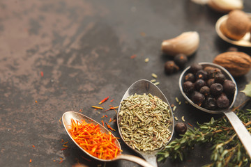 Spoons with herbs and spices on dark old table