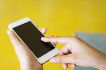 Woman hand shows display mobile smartphone with screen yellow background . Mock up mobile.