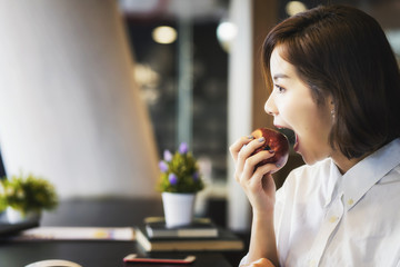 Young Asian female eating an apple.