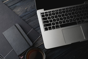 Modern dark surface wooden office desk table with computer and cup of coffee. Hero Header Concept...