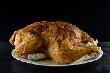 fried chicken whole, on a white plate on a wooden background