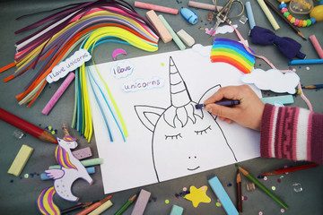 The child draws the unicorn's face with colored pencils on a gray background