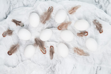 white eggs and brown feathers on a marble counter top