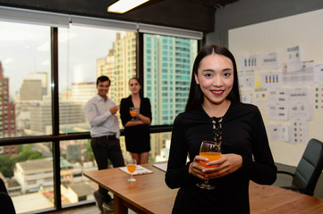 smile of beautiful business woman wear black dress and orange juice on hand at the office, celebrate for business success