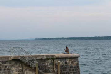 Obraz premium The woman sits on the pier on lake Geneva.