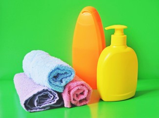 Obraz na płótnie Canvas Soap supplies/ Towels, shampoo and liquid soap on a green background