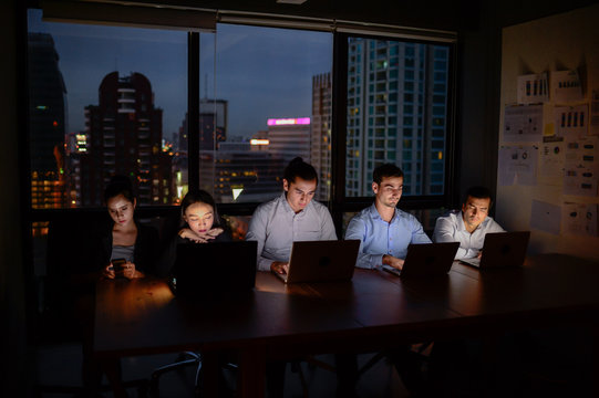 three businessman and two businesswoman working with computer overtime at night