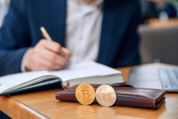 Businessman works in his workplace with notebook, laptop and makes a business plan. Cryptocurrency mining. Golden and silver bitcoin coin. Selective focus.
