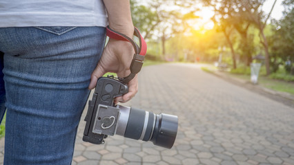 A women  holding   camera and taking a picture of nature on the walk-way