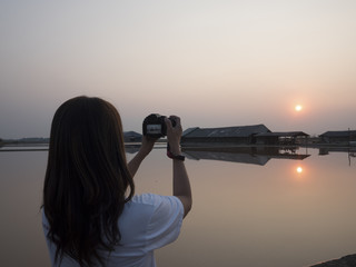 Woman take photos on landscape saline with sunset in golden  sky.