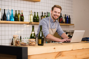 Cheerful positive man standing in front of the laptop