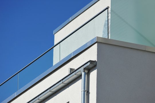 Attika-Profilblech als Mauerschutz und Kasten-Stahl-Dachrinnen am Dachgeschoss eines modernen Mehrfamilienhauses
