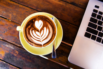 Cup of hot cappucino is on the wooden table