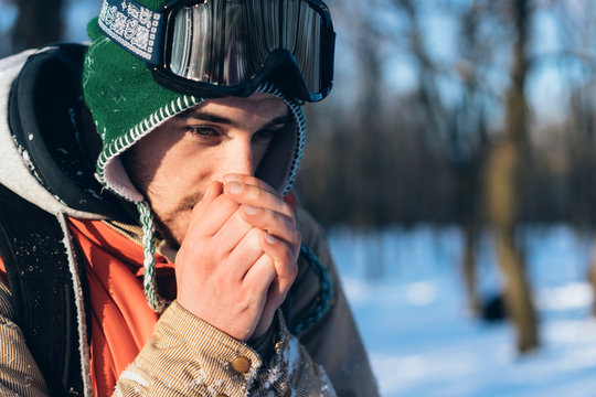 caucasian guy in winterwear  trying to warm his hands outside