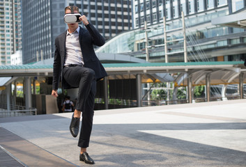 Fototapeta na wymiar Caucasian Businessman wear black suit and Virtual Reality Headset (VR) and fighting by kick to the air