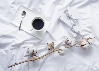 Service à café blanc et fleur de coton en décoration d'intérieur sur un lit de chambre d'hôtel.