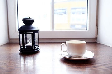 Candle and a cup  on a windowsill
