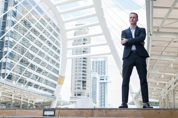 Fototapeta premium Caucasian businessman stand and smile, he looking forward and thinking for successful in career and mission. concept of winner and competition with copy space for text.