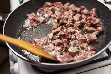 Pan with diced beef on stove. Close up.