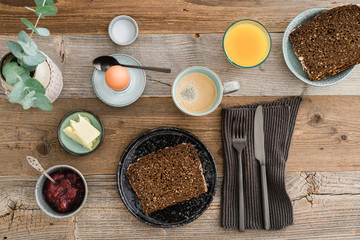 Breakfast table shot from above with bread, egg, coffee, orange juice and jam