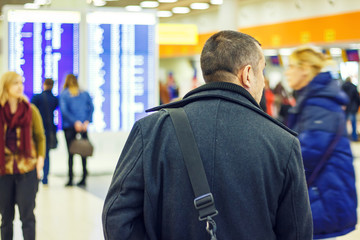 Man with a bag at the airport on the background of an electronic scoreboard