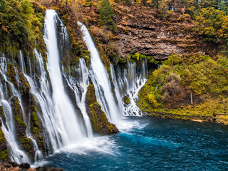 Picturesque waterfall cascade in autumn, surrounded by the moss and yellow bushes. Shot taken in October at McArthur-Burney Falls Memorial State Park, in Shasta County, Northern California.