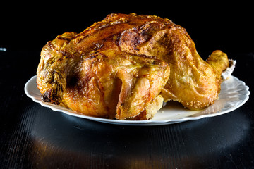 fried chicken whole, on a white plate on a wooden background