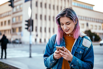 Urban girl with lilac hairstyle using phone at city street.