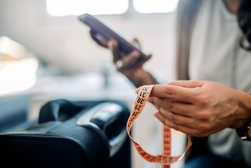 Close-up of female hands holding tape measure.