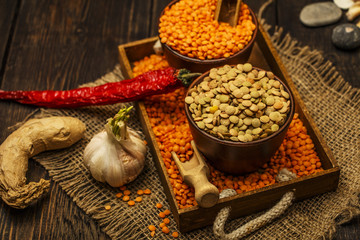 Lentils seeds on a wooden table with sackcloth. Seeds of red and green dietary supplements of lentils. Useful lentils of the legume family.
