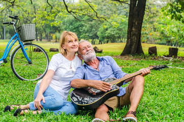 Senior couple loving mature  with guitar at summer field