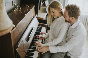 Loving couple playing piano.