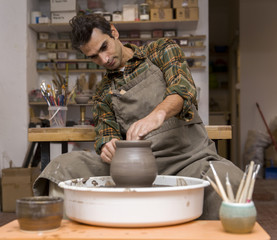 Male artist makes clay pottery on a spin wheel
