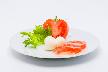 Tomato with cheese and greens on a plate, white background, edible concept.