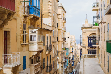 Fototapeta na wymiar Valletta, Malta. Old Town street with traditional maltese balconies and sea view, City of Valletta