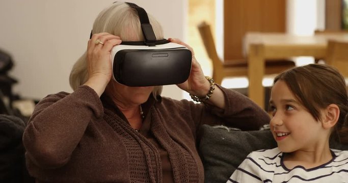 4K Senior lady with her granddaughter experiencing virtual reality viewer for the first time. Slow motion.