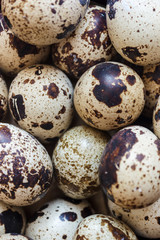 Obraz premium Quail eggs in a clay plate on a wooden background, a plate for storing quail eggs, a symbol of the Easter season. Healthy eating.