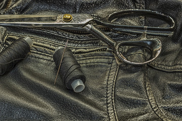 Sewing leather jacket, repair of leather jacket scissors, thread, close-up. Products of leather.