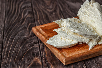 Cheese, cottage cheese on a wooden background, fresh cottage cheese in gauze, dairy product, healthy food. View from above. Goat, cow-baked cottage cheese in a rustic style.