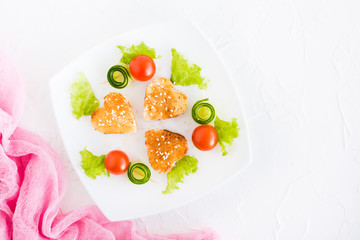 Toasts in the form of heart, cherry and cucumber on a plate. Dish served for lovers. Top view