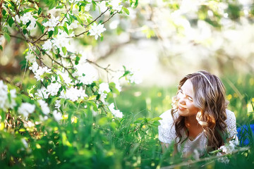 Obraz premium light portrait of an apple tree, girl portrait of a high key, spring mood freshness and purity blonde with long hair in a blooming park in the spring