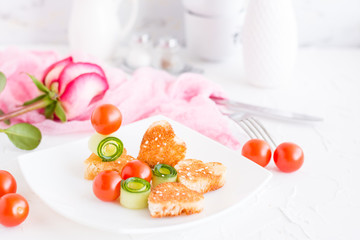 Toasts in the form of heart, cherry and cucumber on a plate. Dish served for lovers and rose.