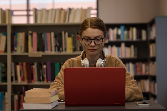 Young woman using a laptop while sitting in library